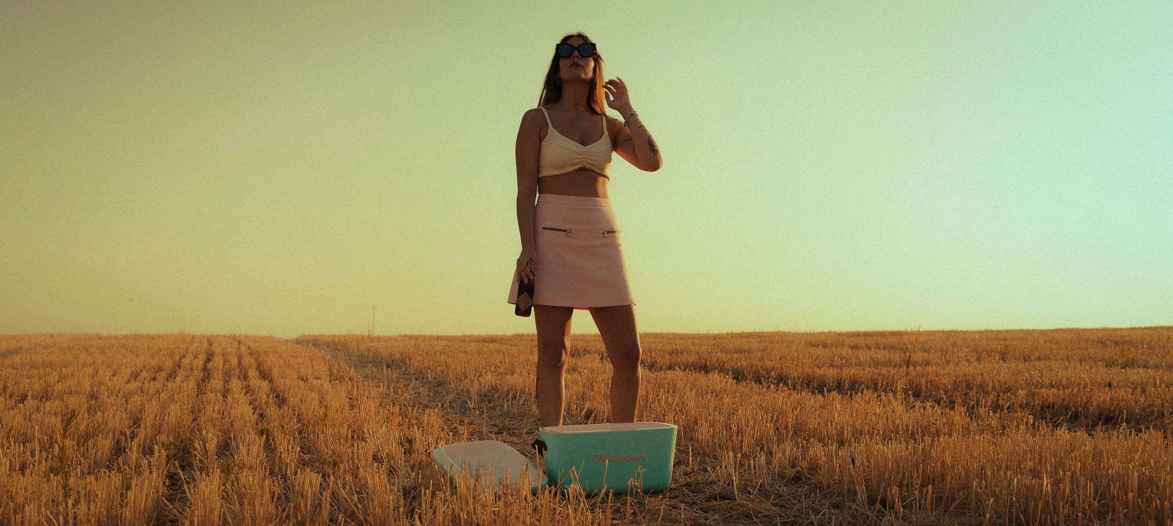 woman in brown tank top and brown skirt standing on brown grass field